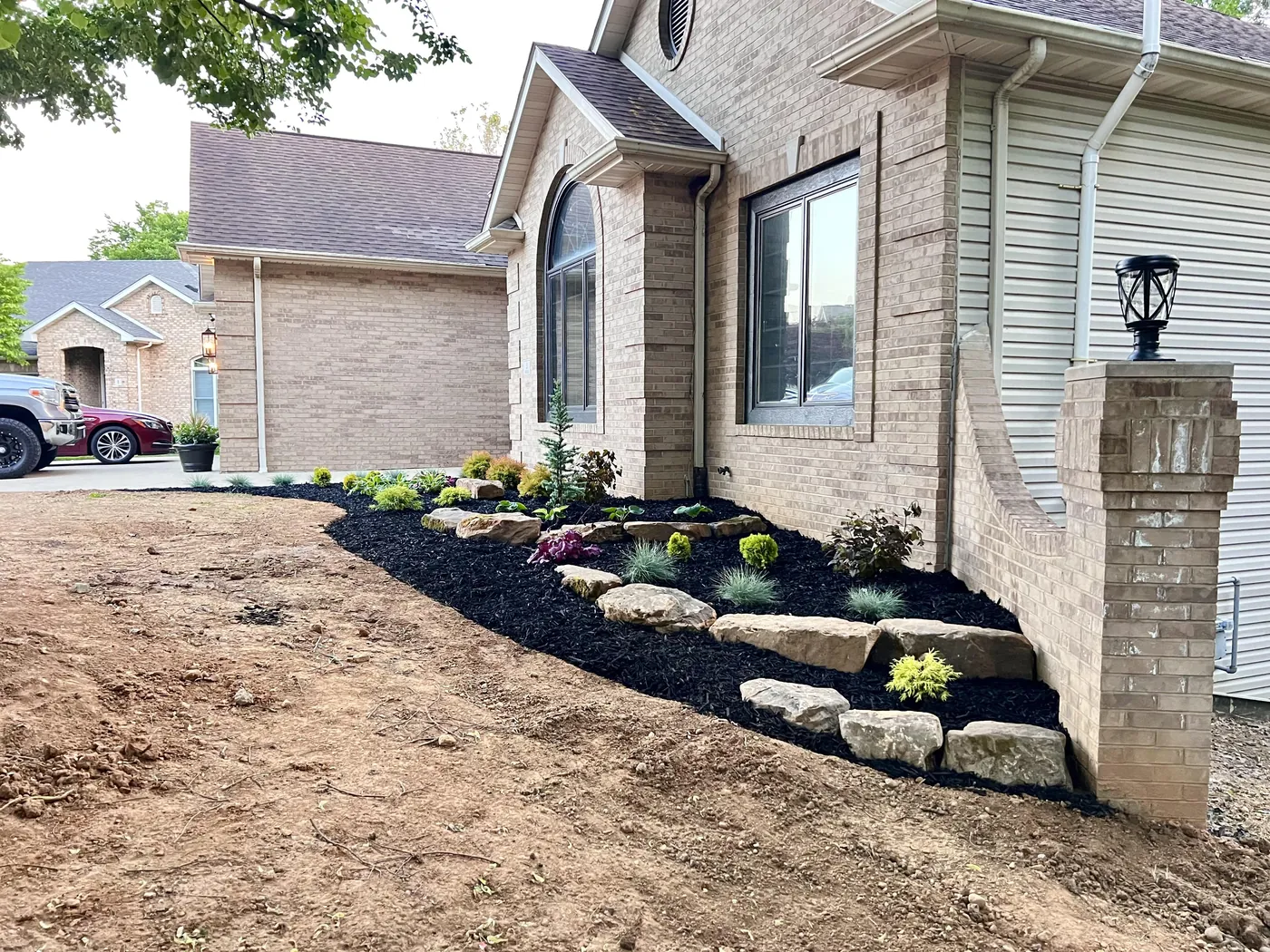 New planting bed of shrubs, boulders and mulch beside a newly built house, before the lawn goes in