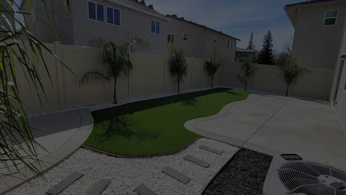 Completed backyard with curved turf and concrete patio at dusk